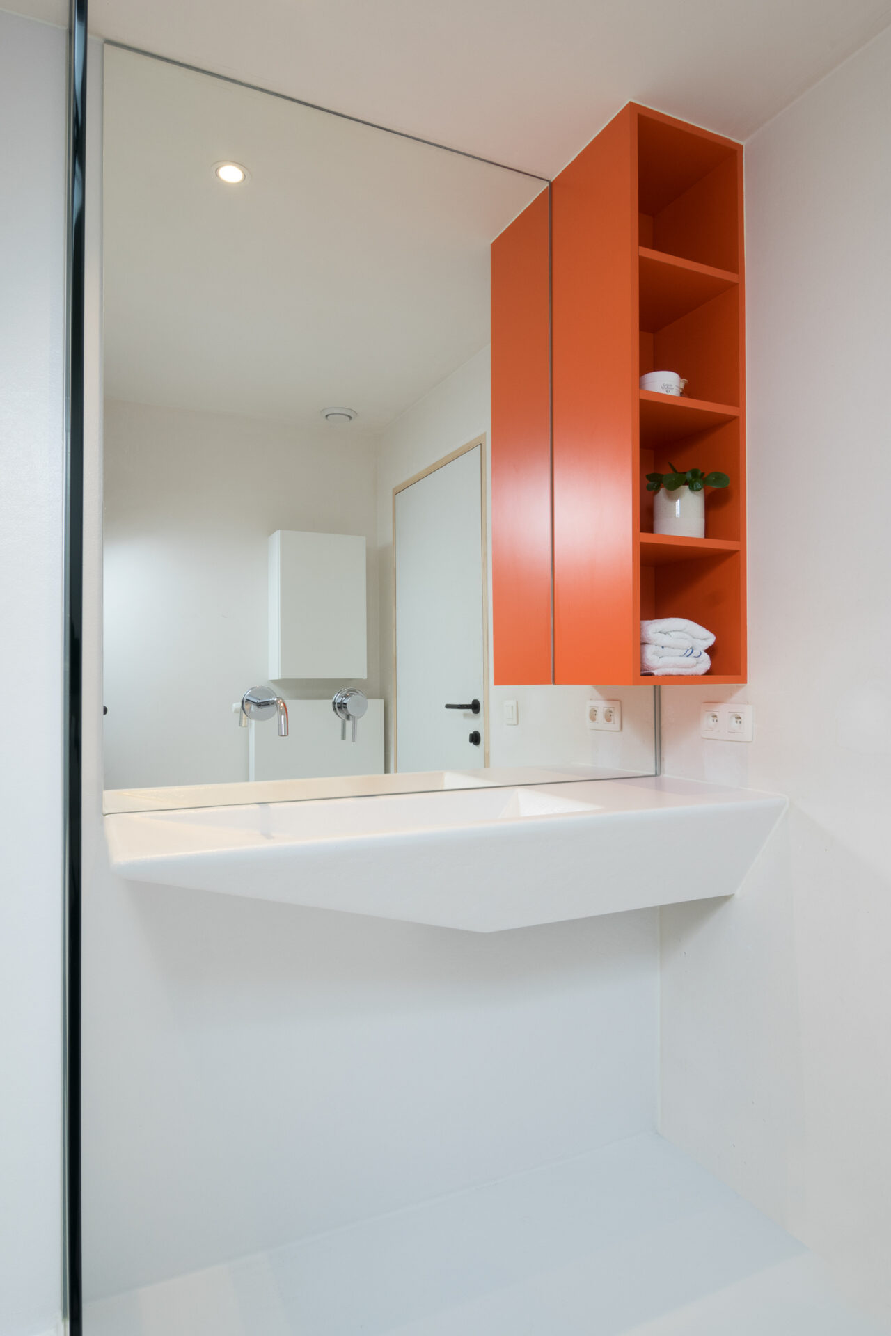 Oranje wandkastje als speels kleuraccent in Voegloze Badkamer te Veurne
