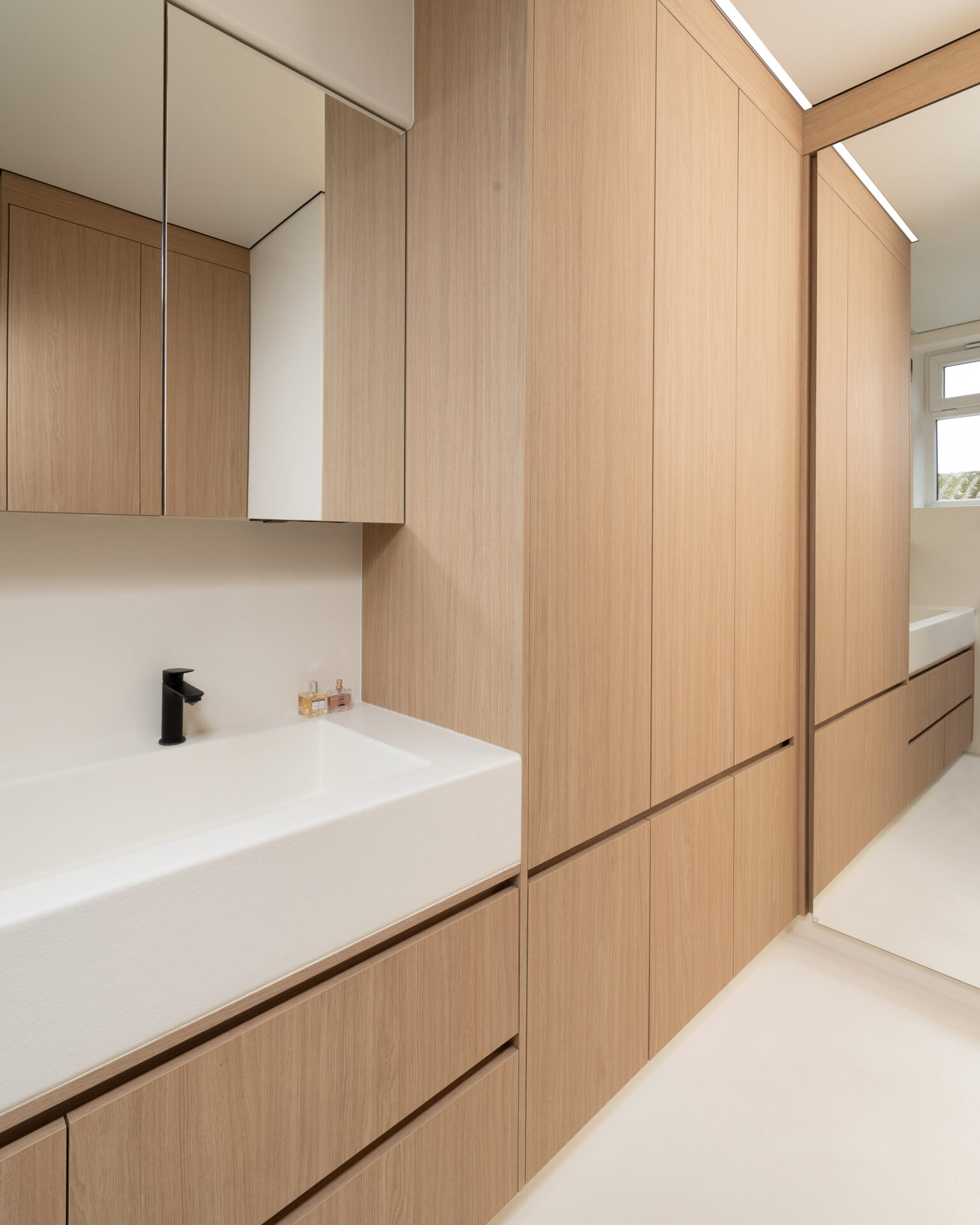 Kleine badkamer met naadloze afwerking en veel kastruimte voor onder andere was- en droogmachine