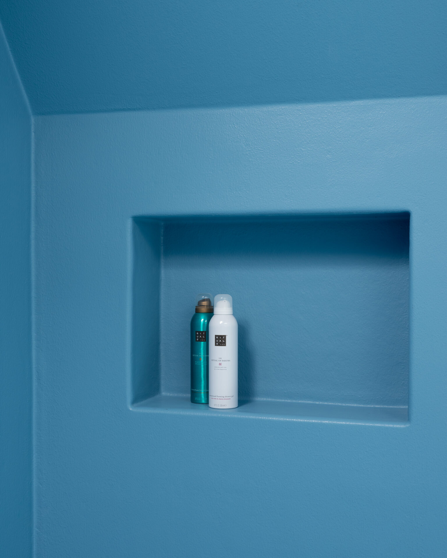 Ingewerkte nisjes als bergruimte in de wand van een blauwe douche